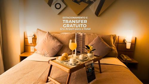 une chambre avec un lit, une table et une coupe de champagne dans l'établissement Hotel aeroporto Guarulhos, à Guarulhos