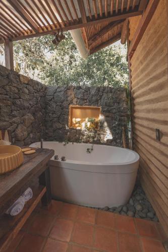 a bath tub in a bathroom with a stone wall at Hotel Ambil in Barichara