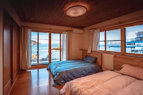 a bedroom with two beds and a view of the ocean at さざなみハウス熱海 in Atami