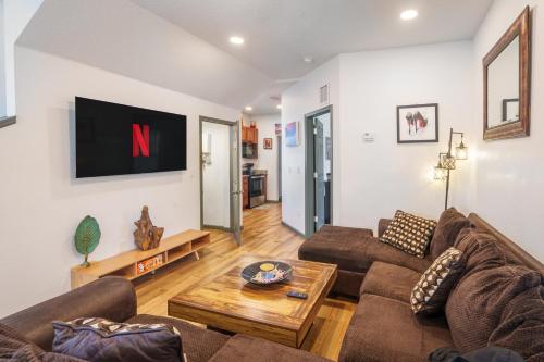 a living room with a couch and a tv on the wall at Stylish & Quiet 3BD Sleeps 8 Near Stadium & Downtown in Jacksonville