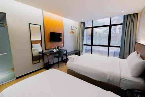 een hotelkamer met 2 bedden, een bureau en een spiegel bij Hotel 99 Seri Kembangan Serdang in Seri Kembangan