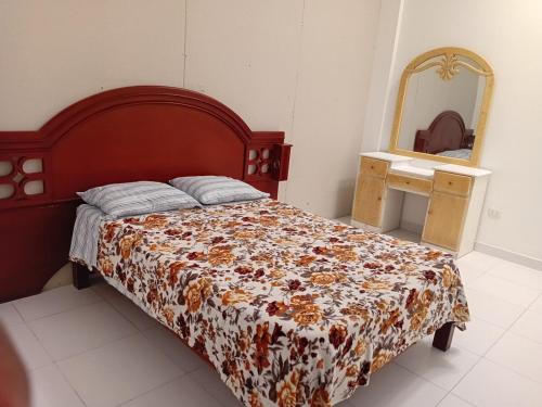 een slaapkamer met een bed met een bloemendeken en een spiegel bij Departamento in Ilo