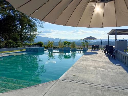 een zwembad met een parasol en een tafel en stoelen bij Finca Maratón Alto in Calarcá