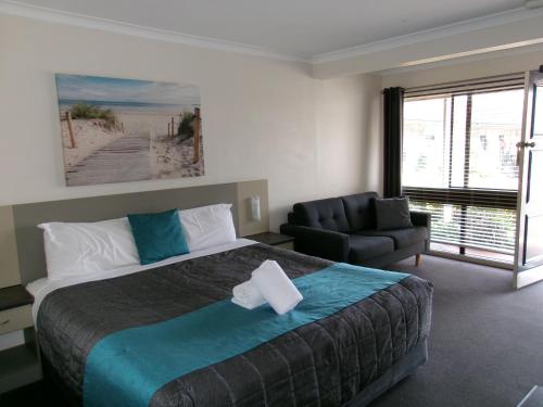 a hotel room with a large bed and a chair at Caravilla Motor Inn in Taree