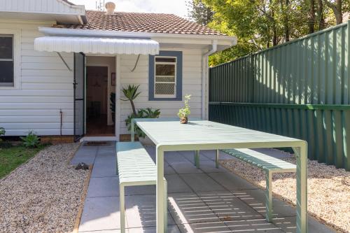 a picnic table and two benches in front of a house at Hibiscus Cottage in Ballina