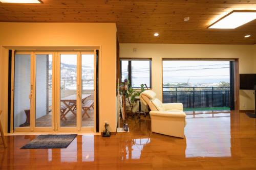 a living room with a white chair and sliding glass doors at さざなみハウス熱海 in Atami