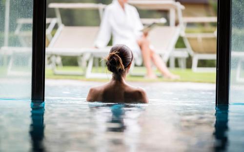 a woman in the water in a swimming pool at Hotel Angelo Engel in Ortisei