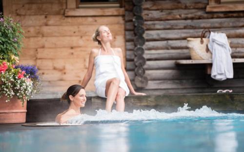 a woman sitting on the edge of a swimming pool at Hotel Angelo Engel in Ortisei