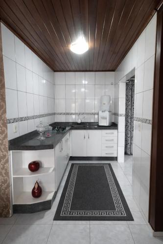 a kitchen with white tiled walls and a counter at Casa com Piscina e Jacuzzi, Próxima da Praia Brava in Itajaí