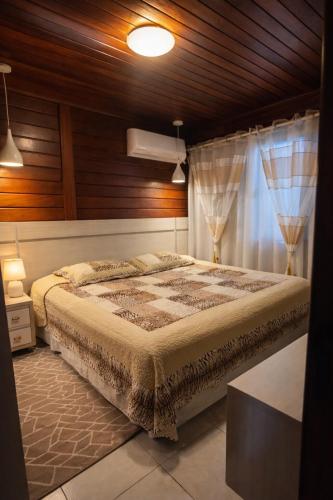 a bedroom with a large bed and a window at Casa com Piscina e Jacuzzi, Próxima da Praia Brava in Itajaí