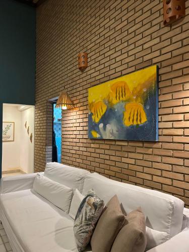 a white couch in a room with a painting on the wall at Casa do Luar I Alagoas I Nordeste-Coruripe in Coruripe
