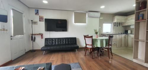 een woonkamer met een tafel en een zwarte leren bank bij Detached house on the second floor in Santiago