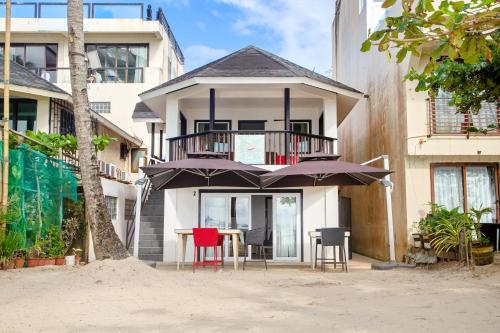 een huis met een tafel, stoelen en parasols bij La Suerte Villa in Boracay