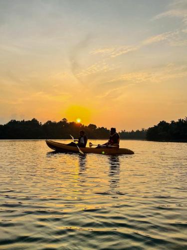 twee mensen in een kano op een meer bij zonsondergang bij Crush River Villa Hikkaduwa in Hikkaduwa