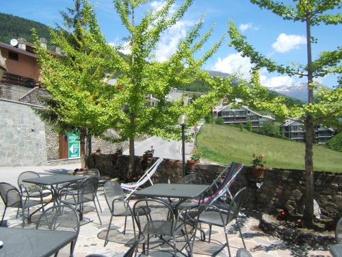 a patio with tables and chairs and trees at Hotel Ristorante Miravalle in Teglio