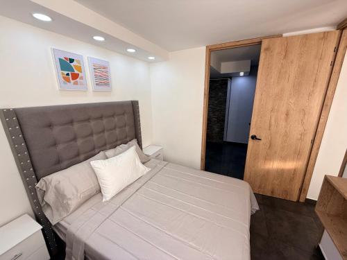 een slaapkamer met een groot bed met een bruin hoofdeinde bij Apartamento Moderno en Villeta - Nido de San Miguel in Villeta