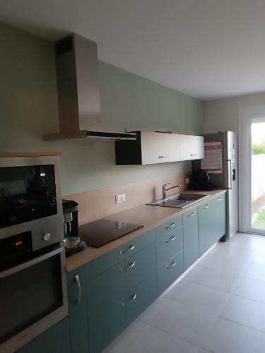 una cucina con armadi blu, lavandino e forno a microonde di Maison proche circuit 24h ad Arnage
