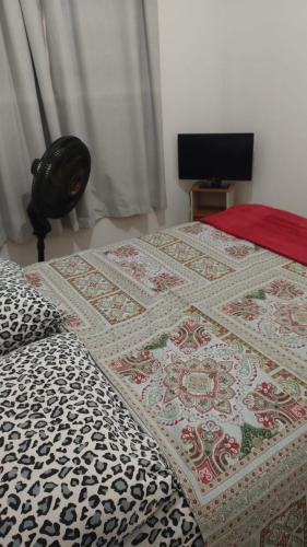 a bed with a quilt on it in a bedroom at APTO EASY Poços de Caldas in Poços de Caldas