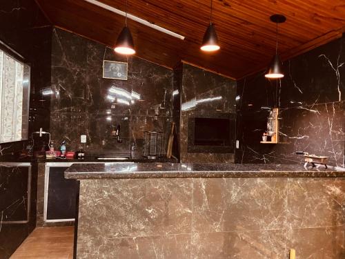 a kitchen with black marble counters and pendant lights at Recanto orti in Olímpia