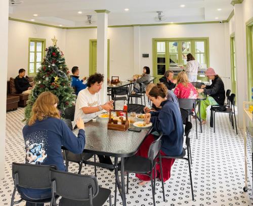 a group of people sitting at tables in front of a christmas tree at White Elephant Hostel in Luang Prabang
