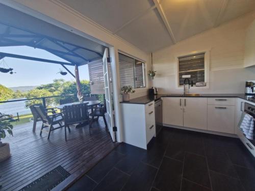 een keuken met een balkon met een tafel en stoelen bij Tweed River Waterfront Cottage in Murwillumbah