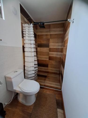 a bathroom with a toilet and a wooden wall at El Embeleso in Nobsa