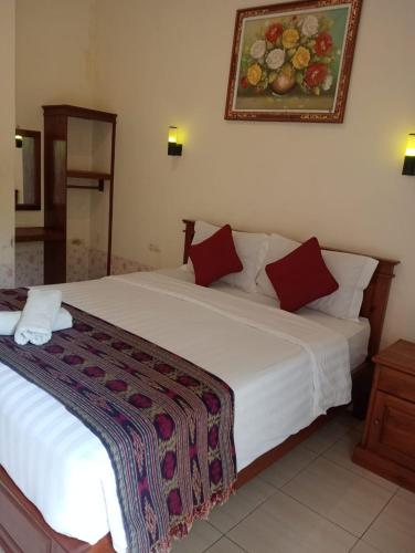 a bedroom with a large white bed with red pillows at Yudhist Guest House in Nusa Lembongan