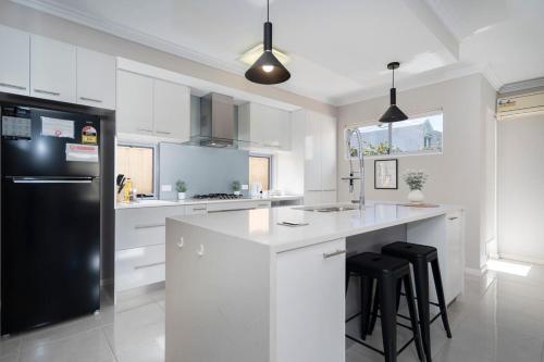 a kitchen with white cabinets and a black refrigerator at 30 Modern & Quiet Retreat -Walk to Dining & Shops in Perth