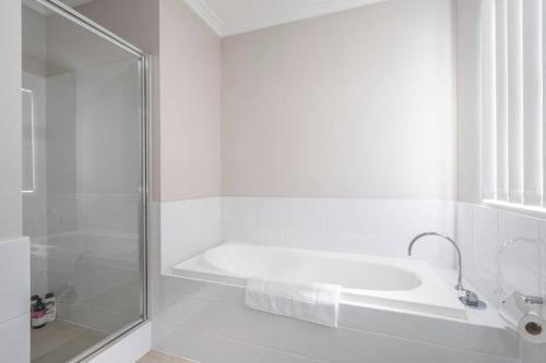 a white bathroom with a shower and a bath tub at 30 Modern & Quiet Retreat -Walk to Dining & Shops in Perth