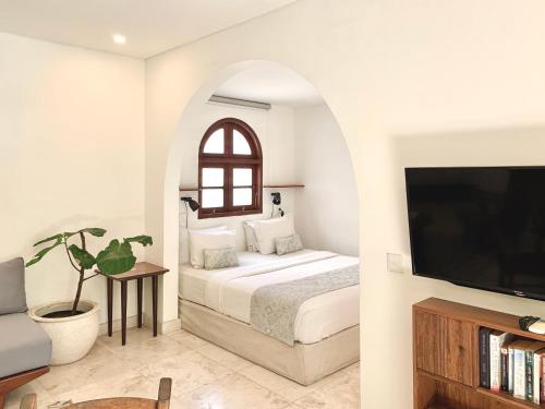 a bedroom with a bed and a tv at Kresna By The Sea By Kresna Hospitality in Seminyak