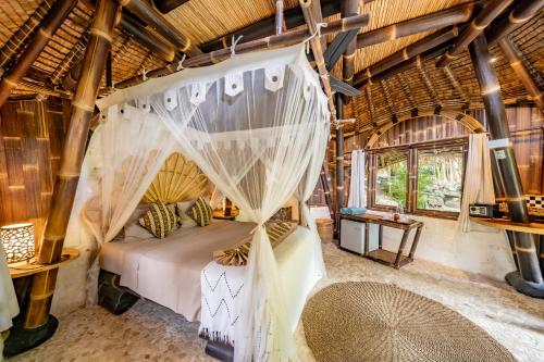 une chambre avec un lit avec moustiquaire dans l'établissement Le Bamboo Bali, à Uluwatu
