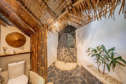 La salle de bains est pourvue de toilettes et d'une douche en pierre. dans l'établissement Le Bamboo Bali, à Uluwatu