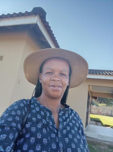 een vrouw met een rieten hoed lacht naar de camera bij Lushaba's modern bliss in Paddock