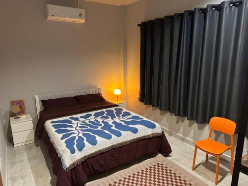 een slaapkamer met een bed en een oranje stoel bij Hill View Home 3 in Ko Pha Ngan