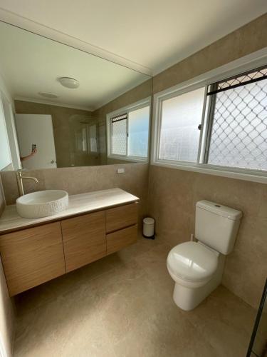 un bagno con un water, un lavandino e uno specchio di The Mooloolaba Terrace a Mooloolaba