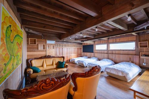 een kamer met 4 bedden en een bank en stoelen bij マーレゲストハウス in Fukui
