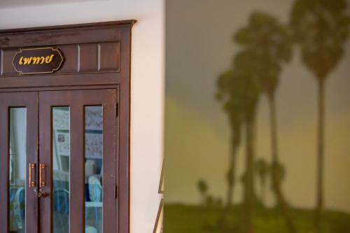 een deur van een gebouw met palmbomen op de achtergrond bij Royal Diamond Hotel in Phetchaburi