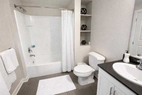 a white bathroom with a toilet and a sink at Luxury Residence Loft 3 Beds with Pool and Gym in Los Angeles