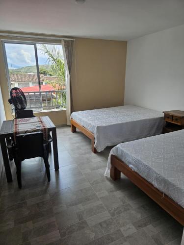 a bedroom with two beds and a desk and a window at Alpha1 in Roldanillo