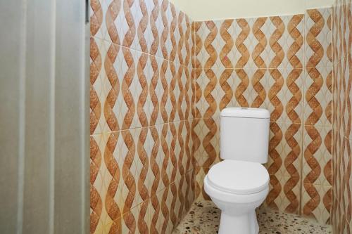 a bathroom with a white toilet in a room at Hotel O Roda Inn in Padang