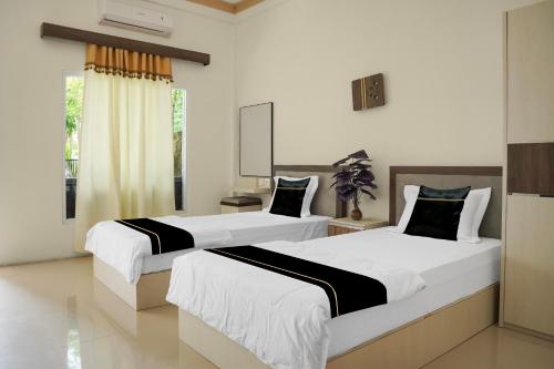 two beds in a hotel room with at Hotel O Roda Inn in Padang