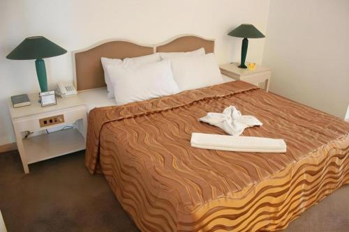 een slaapkamer met een groot bed met twee nachtkastjes bij Hotel Supreme in Baguio