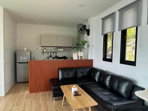 a living room with a black leather couch and a table at Love koh tao villa 2 in Koh Tao