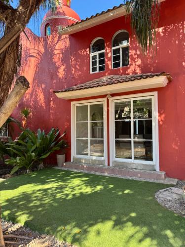 a red house with a lawn in front of it at Casa Arcángel SM in Cruz de Huanacaxtle