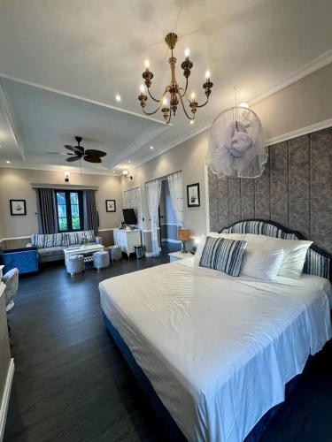 a bedroom with a large white bed and a living room at Vườn vua resort- Sunvillas in Ðồng Phú
