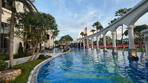 a swimming pool at a resort with a fountain at Vườn vua resort- Sunvillas in Ðồng Phú