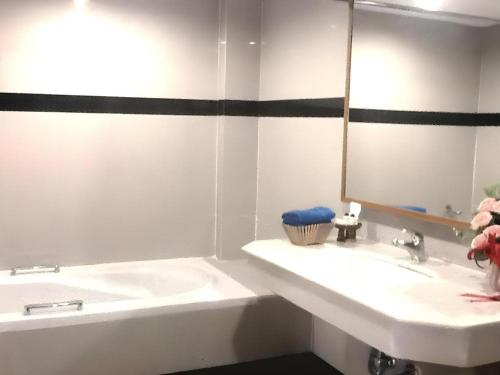 a bathroom with a sink and a mirror and a tub at PC Palace Hotel in Sakon Nakhon