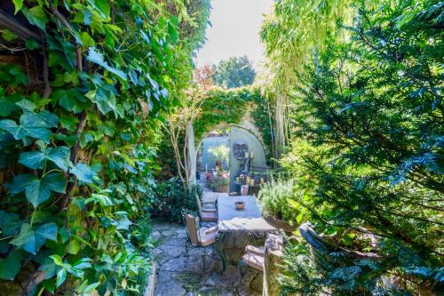 a garden with an archway and a table and chairs at Romantic Provence Pool & Mill View in Goult