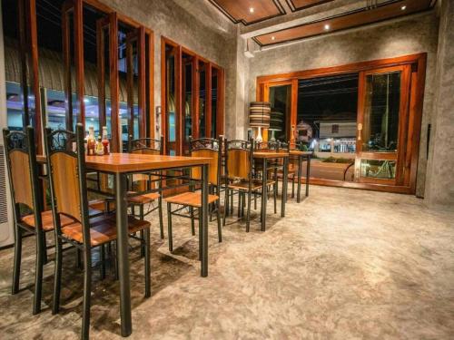 a dining room with tables and chairs and windows at Theloft boutique nakhonpanom in Ban Noi Pho Kham