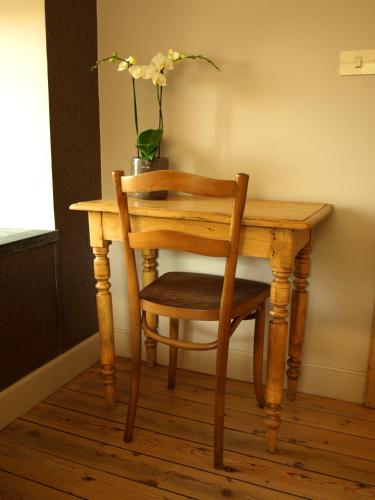 a wooden table with a chair and a vase with flowers at B&B Pastorie van Merkem in Merkem